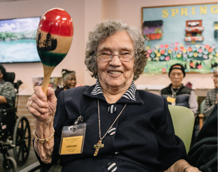 A participant in the Adult Day Program smiles for the camera while participating in a music activity