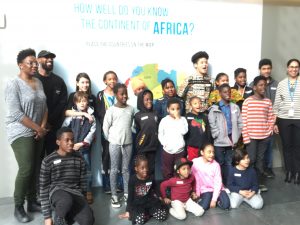 Many members of the Roots and Culture Gardening Club posing in front of a photo backdrop