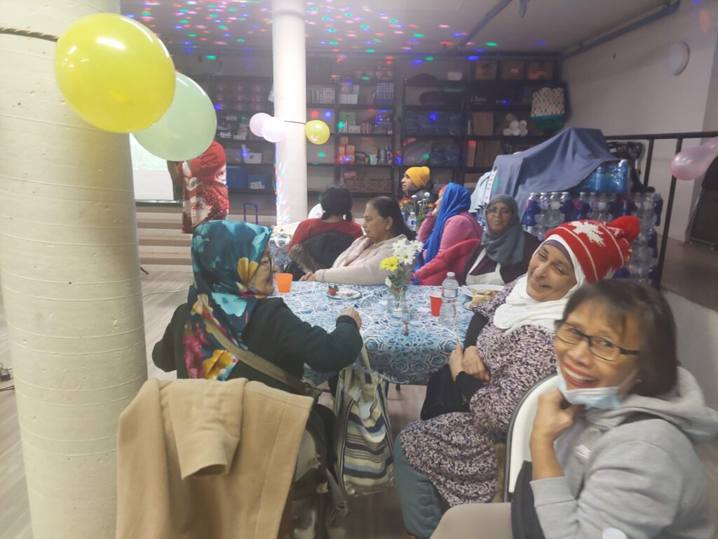 Several women sitting around a table, with balloons.