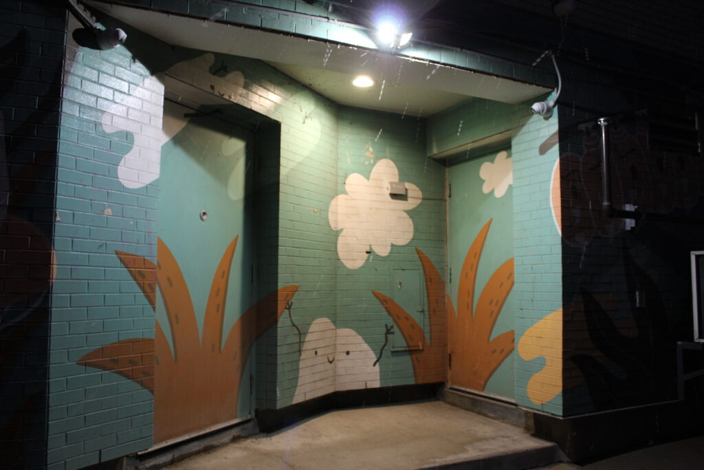 Doorway with street art, trees and cloud shapes.