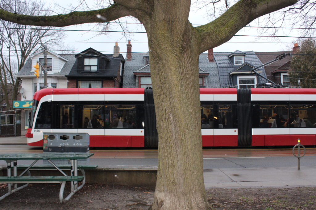 A street car going by and a tree in front of it.