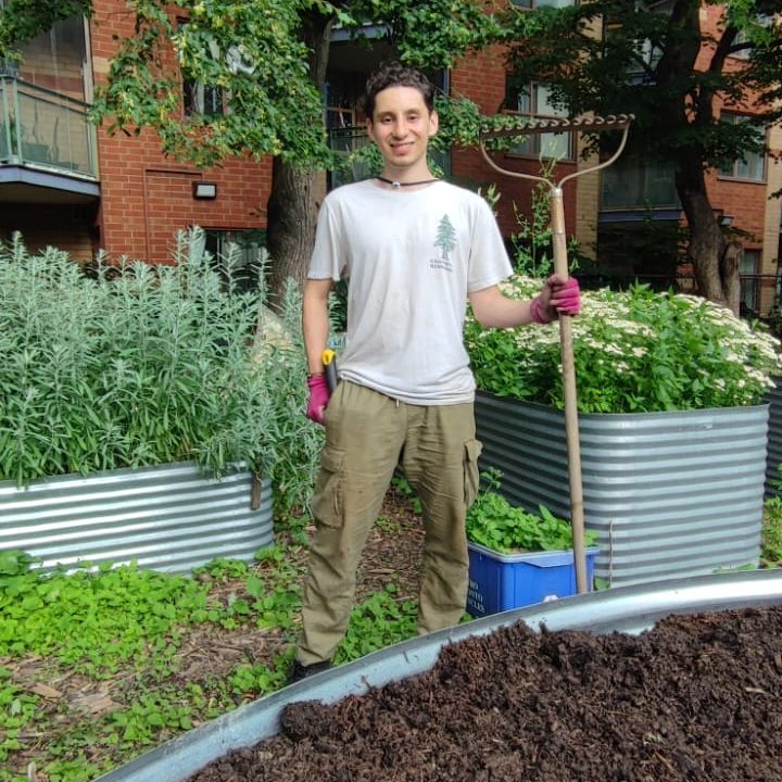 Person standing in a garden with a spade.