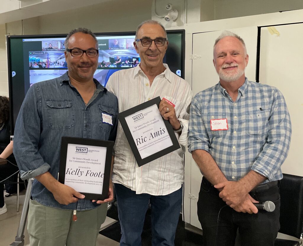 Three men standing for a photo. Two have plaque with names on them.